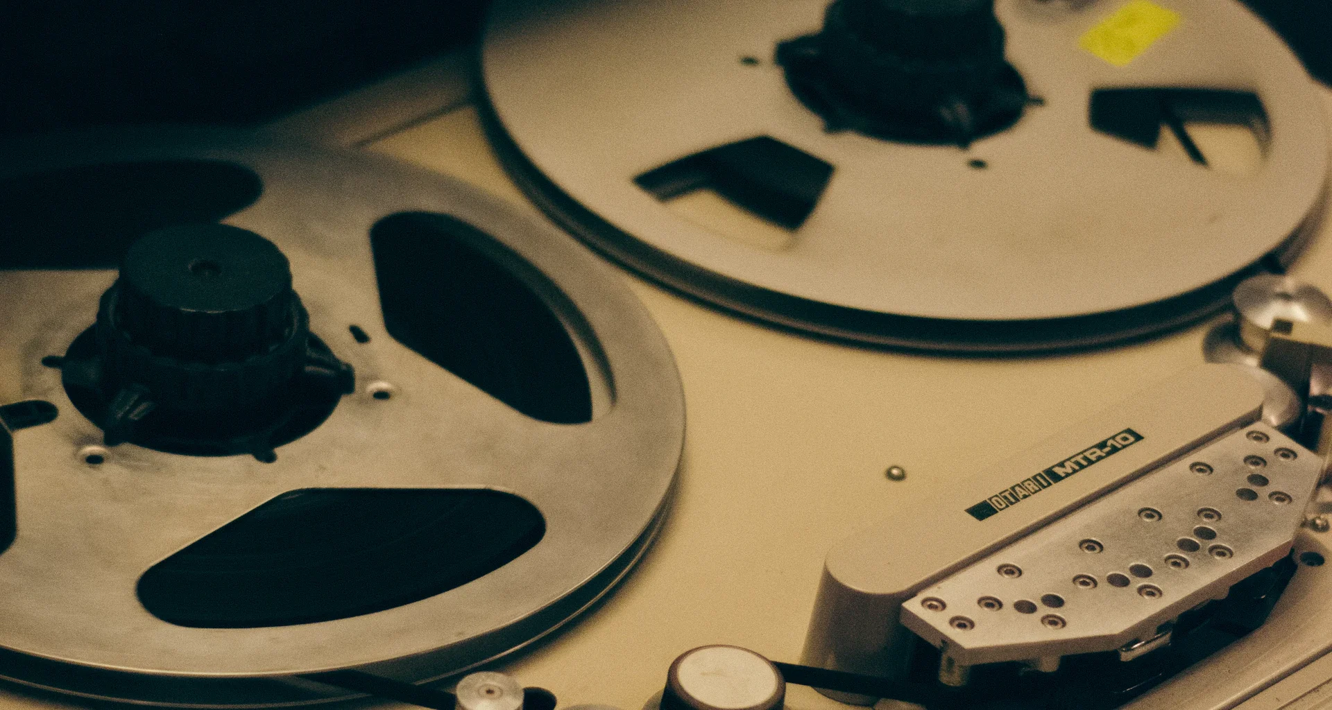 Close-up of the reels on a vintage reel-to-reel tape recorder in warm light