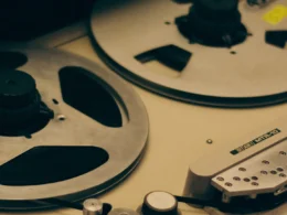 Close-up of the reels on a vintage reel-to-reel tape recorder in warm light
