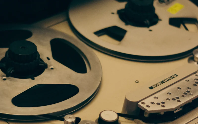 Close-up of the reels on a vintage reel-to-reel tape recorder in warm light
