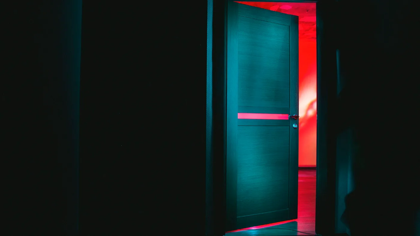 Reflection AI Beam: partly open door revealing a bright red room in the dark.