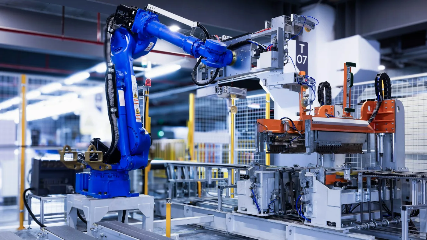 Robots vs human labour cost: blue industrial robot arm standing in a factory.