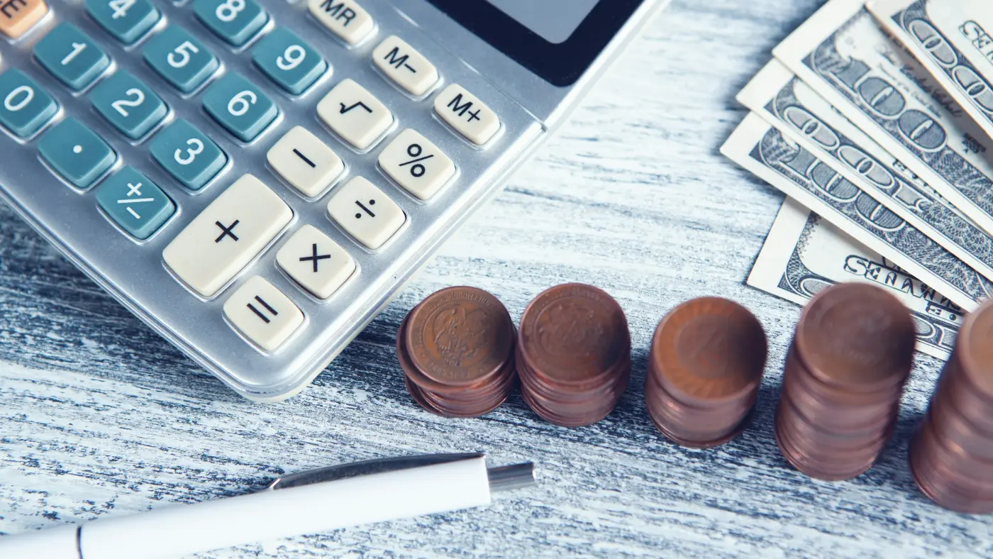 Calculator, pen and money laid out on a table.