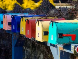 A row of colourful mailboxes beside a bush