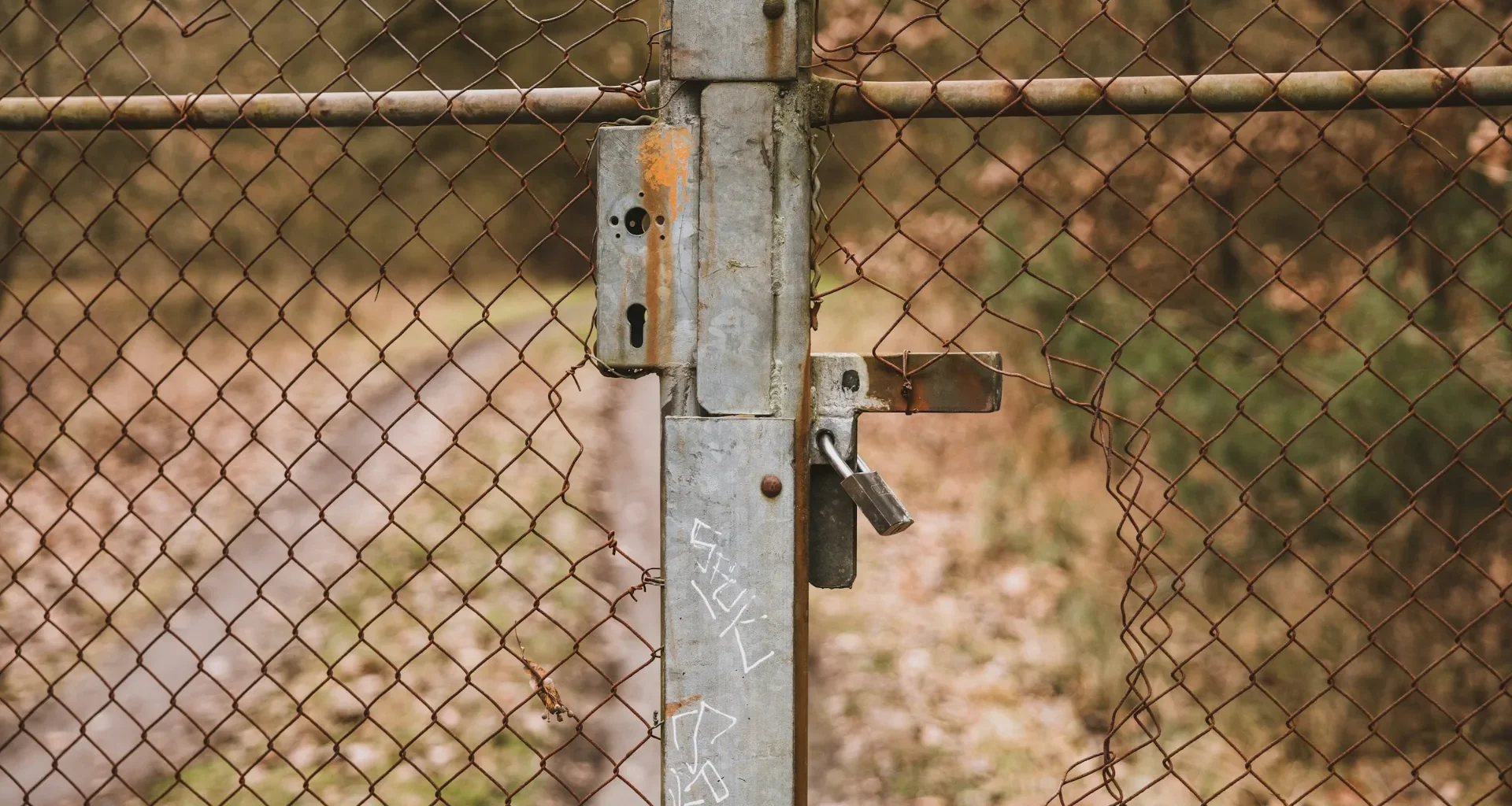 A rusted metal gate closed with a padlock
