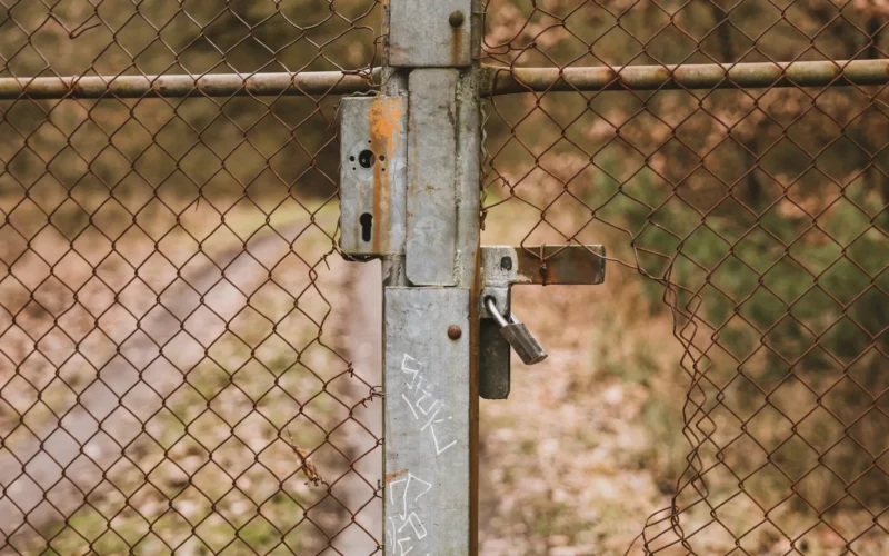 A rusted metal gate closed with a padlock