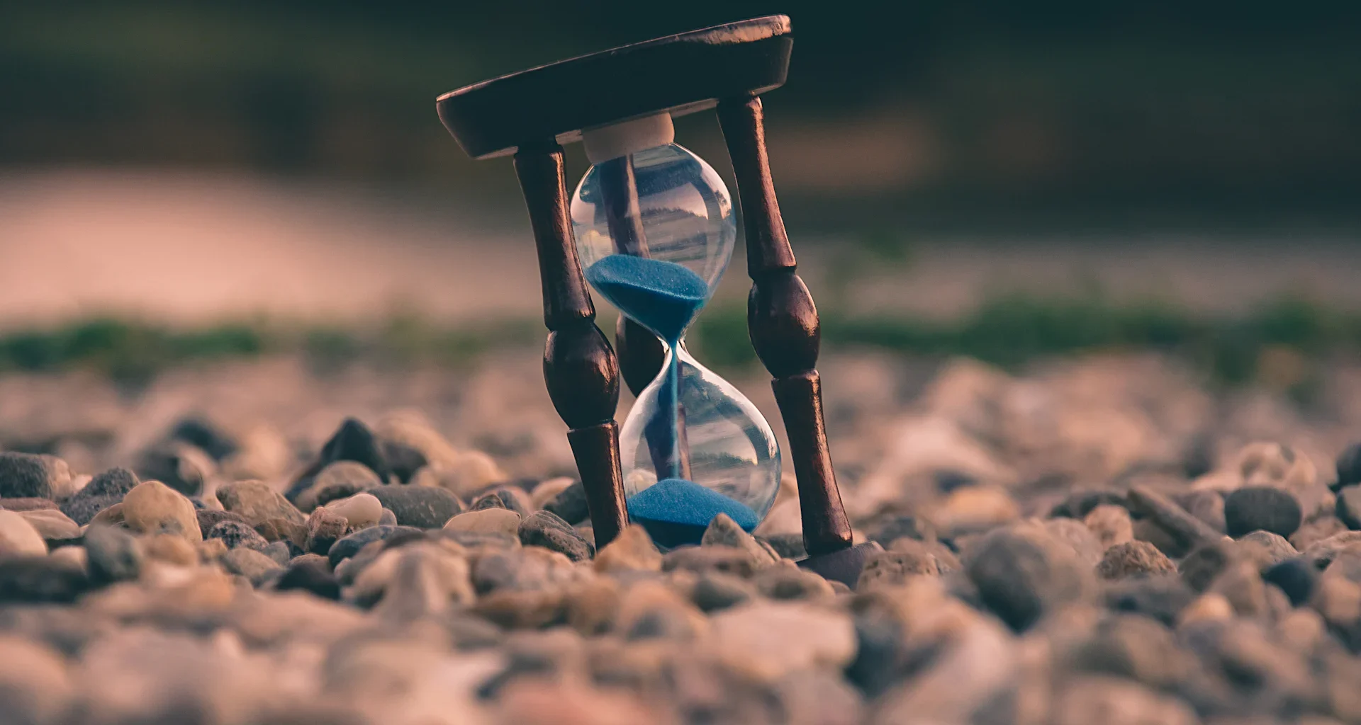 Selective focus photo of brown and blue hourglass on stones
