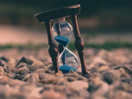 Selective focus photo of brown and blue hourglass on stones