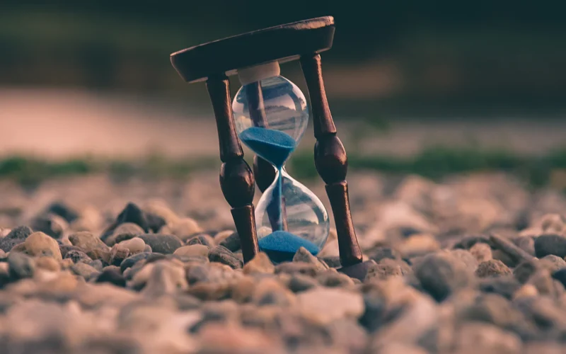 Selective focus photo of brown and blue hourglass on stones