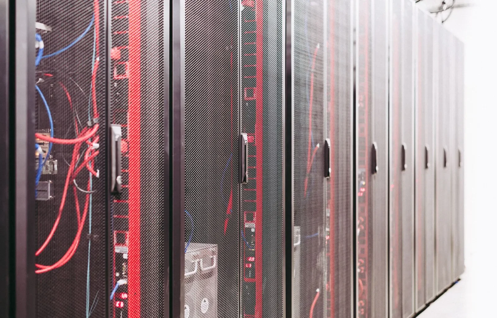 Rows of server racks with red and blue cables in a data centre.
