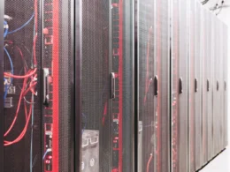 Rows of server racks with red and blue cables in a data centre.