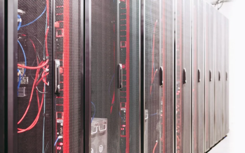 Rows of server racks with red and blue cables in a data centre.