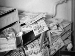 A stack of folded newspapers piled on a newsstand shelf