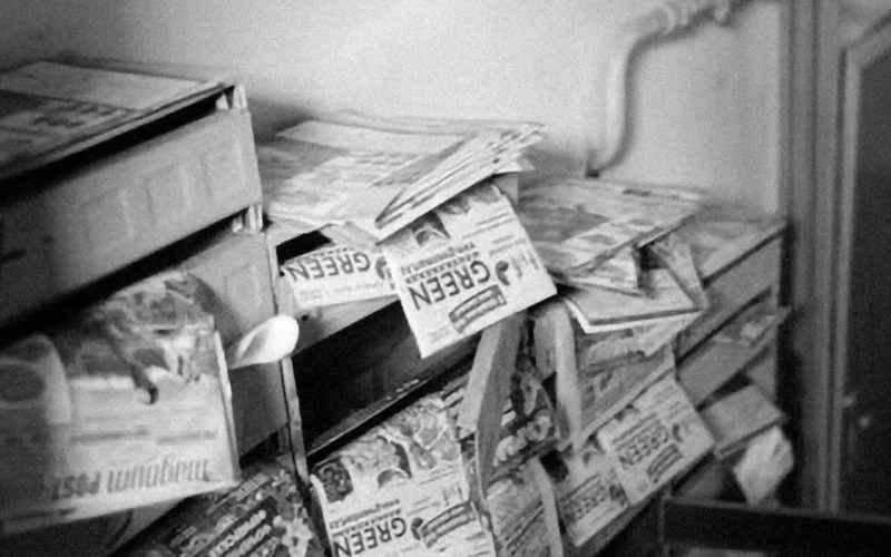 A stack of folded newspapers piled on a newsstand shelf