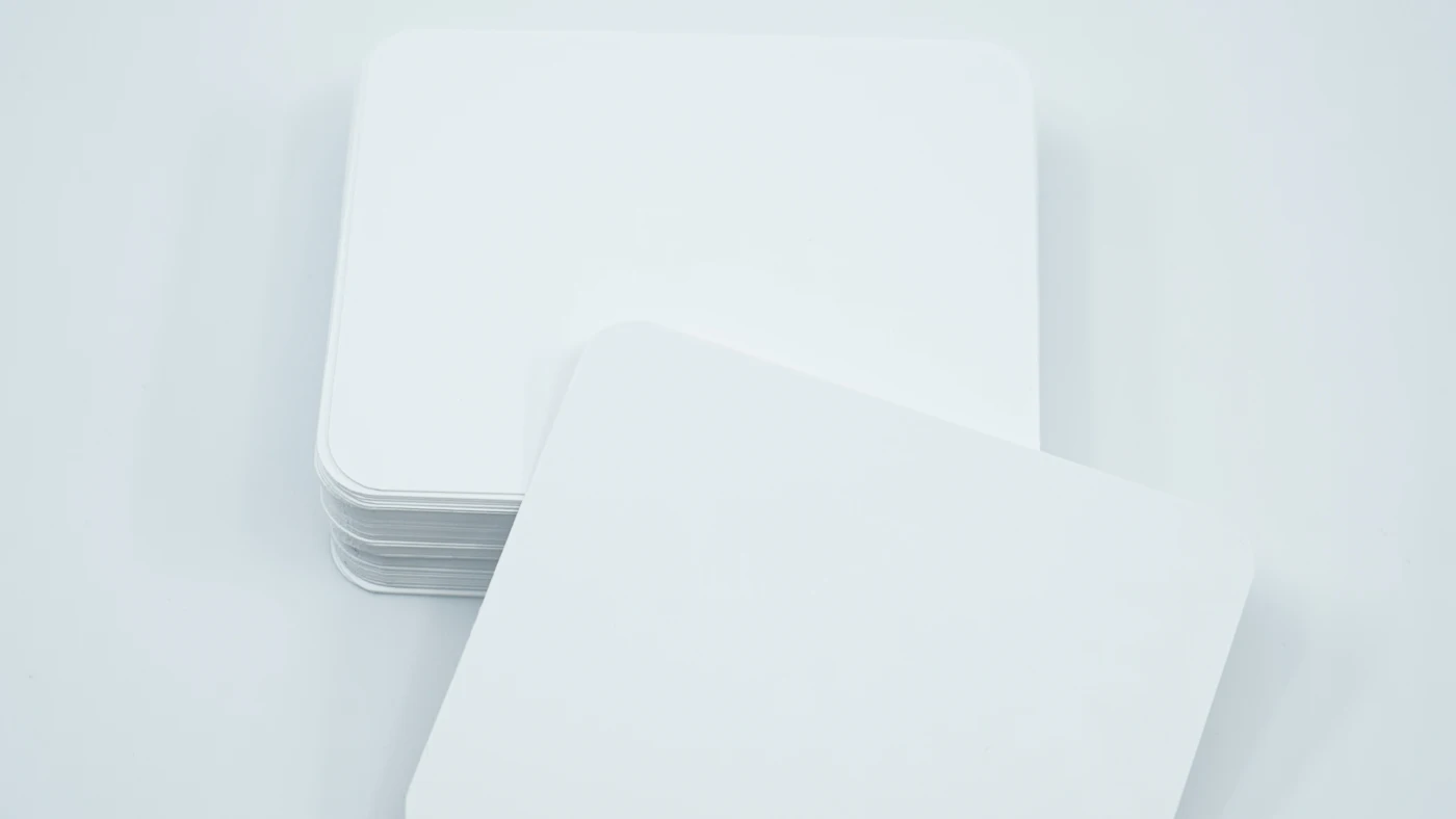 Stack of blank white cards with rounded corners on a pale grey surface