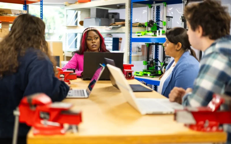 Staff working on laptops around a workshop table, the kind of team AI training in Canada is meant to reach