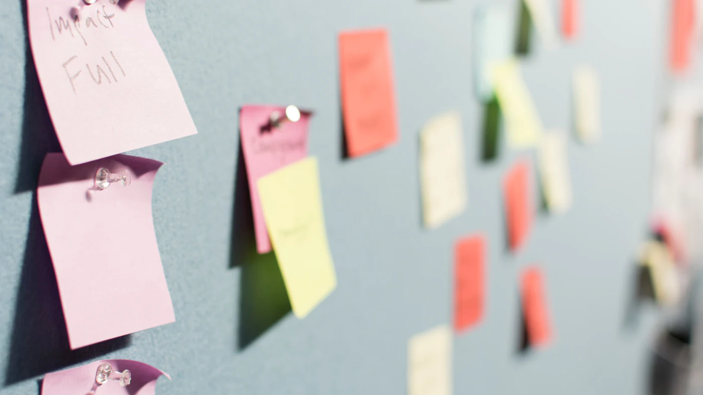 Coloured sticky notes pinned to a grey planning board