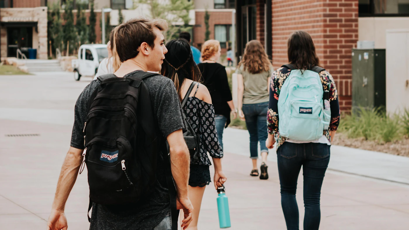 Students with backpacks walking along a campus sidewalk