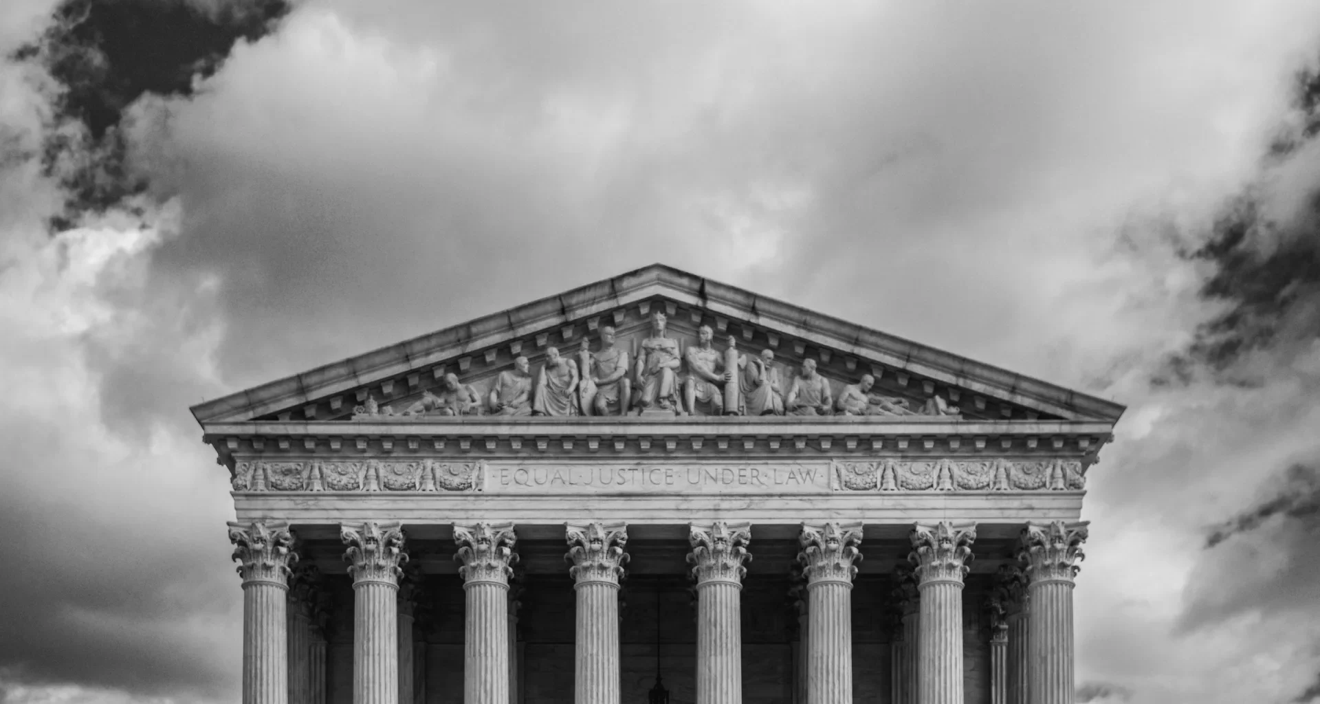Black and white view of the US Supreme Court building with its columns and sculpted figures
