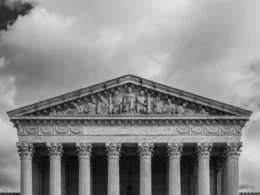 Black and white view of the US Supreme Court building with its columns and sculpted figures