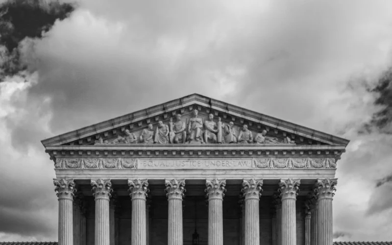 Black and white view of the US Supreme Court building with its columns and sculpted figures
