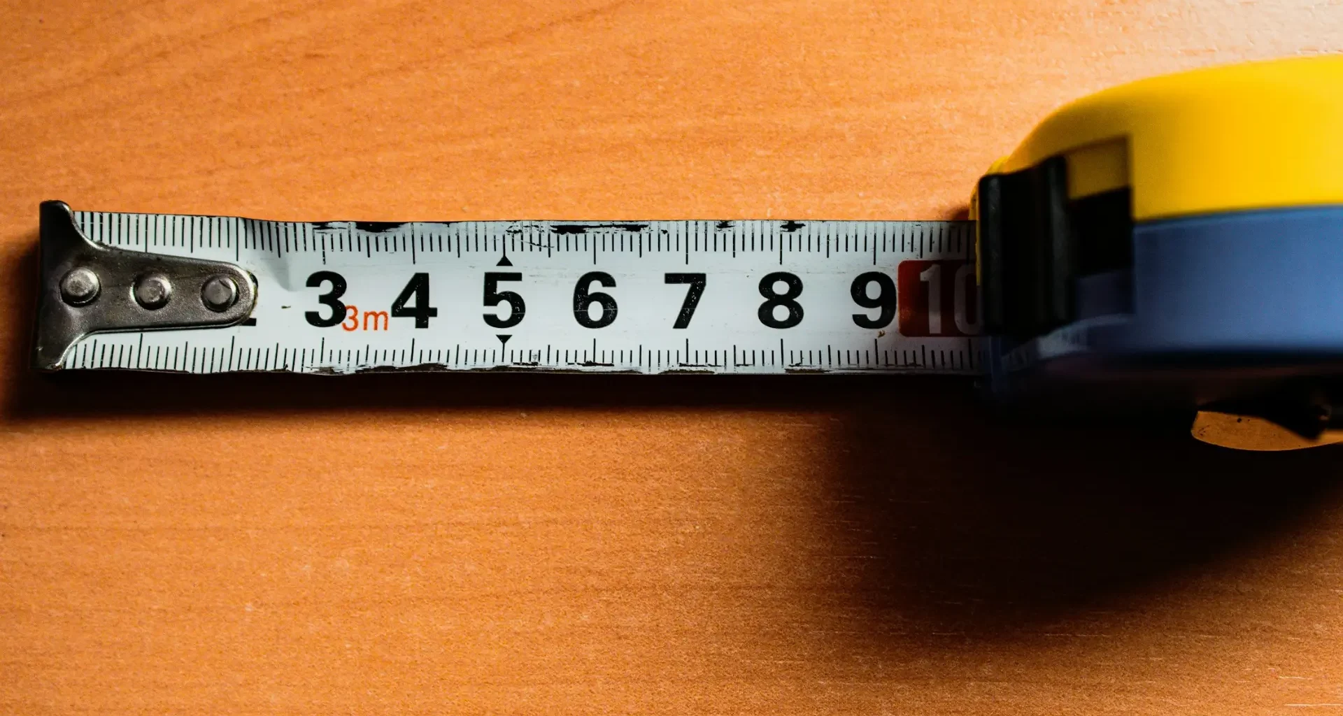 A colour tape measure with centimetre markings laid across a wooden surface
