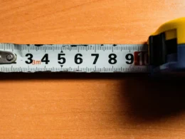 A colour tape measure with centimetre markings laid across a wooden surface
