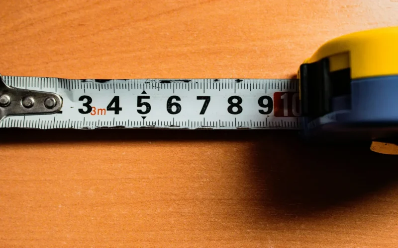 A colour tape measure with centimetre markings laid across a wooden surface