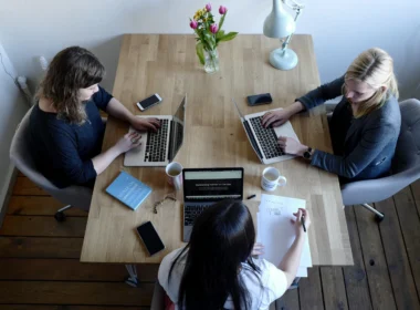 Three women sitting around a table using laptops
