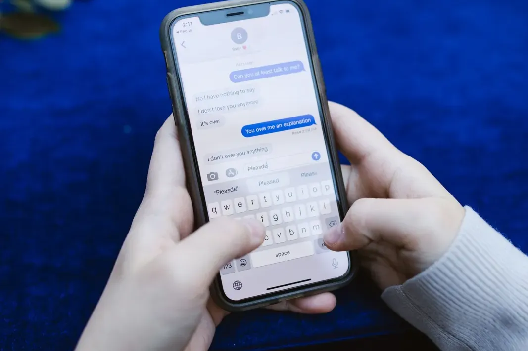 Two thumbs typing a message on a smartphone over a blue surface, a reminder that a personal AI agent policy covers what gets sent