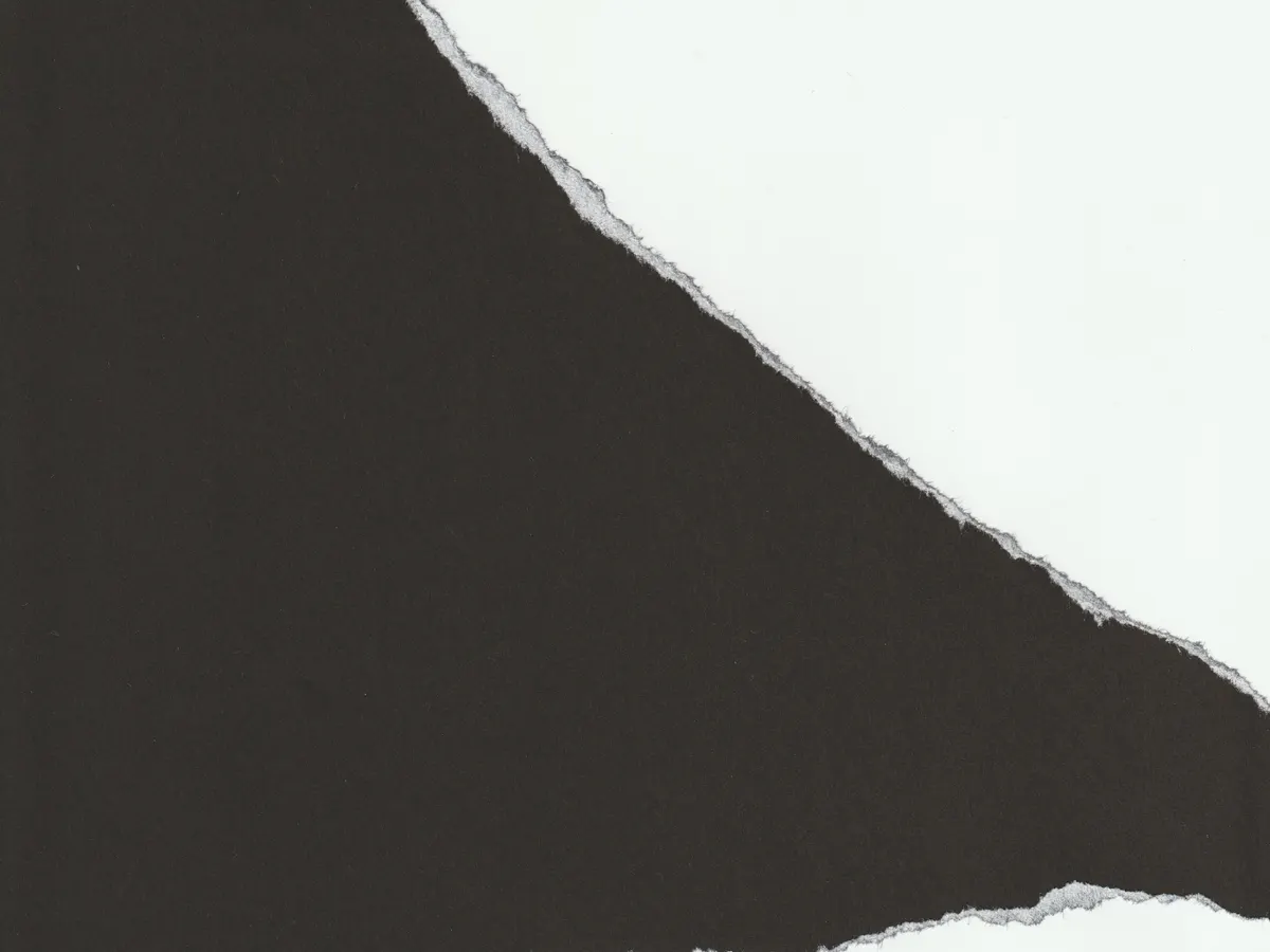 Torn black and white paper along a ragged edge, an abstract image of the two options in a human in the loop AI review