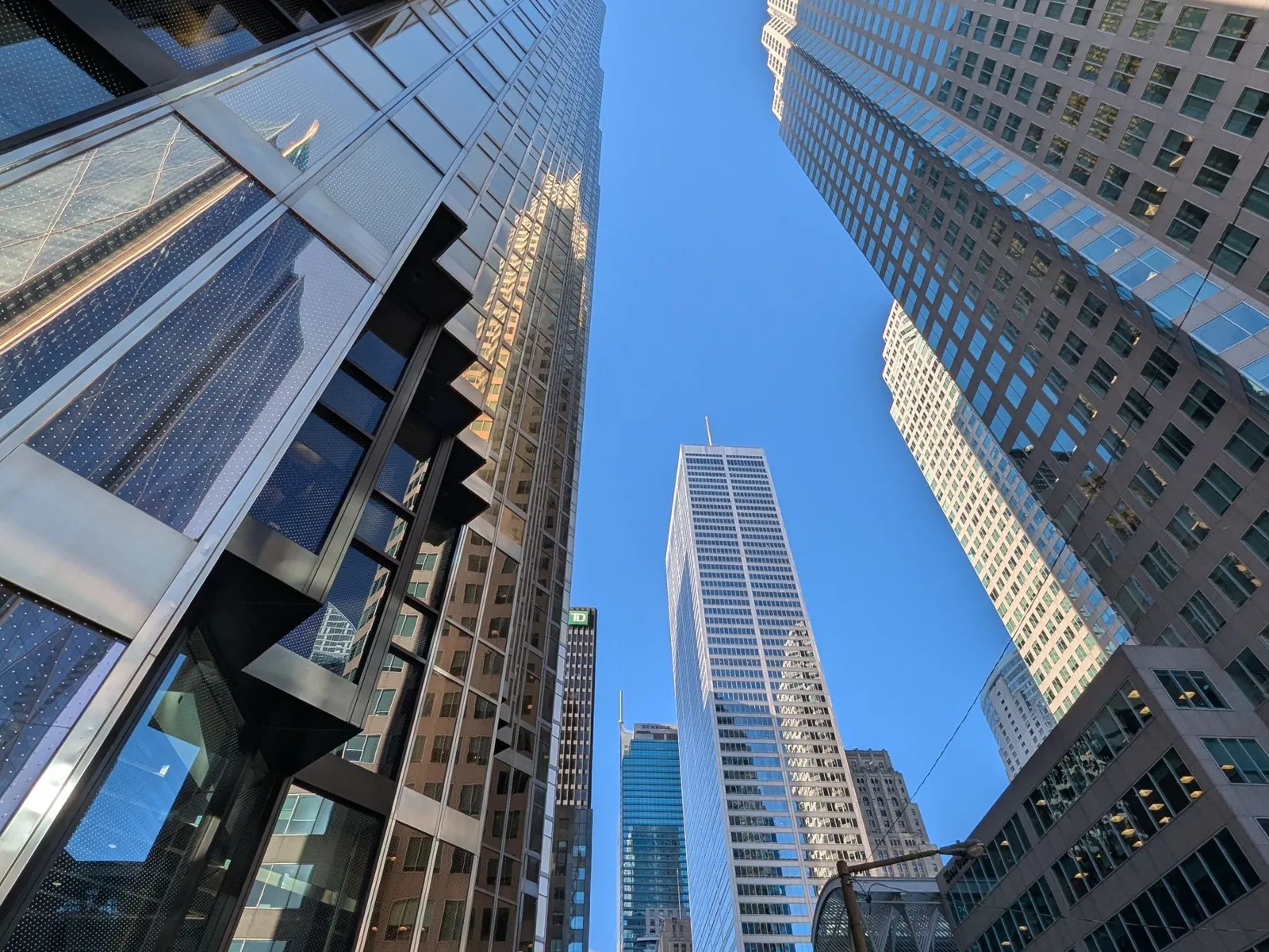 Glass towers in Toronto's financial district seen from street level against a blue sky