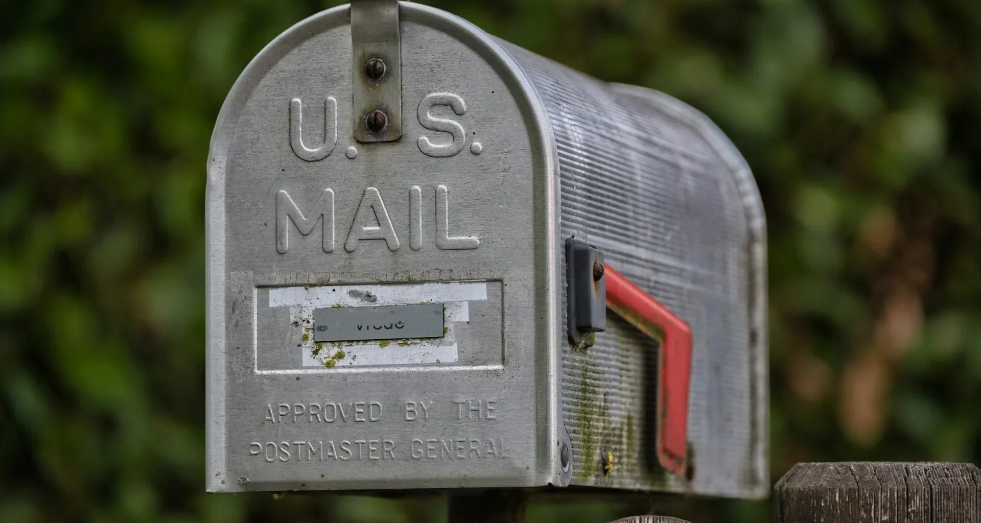 A weathered roadside mailbox with its red flag raised
