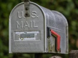 A weathered roadside mailbox with its red flag raised