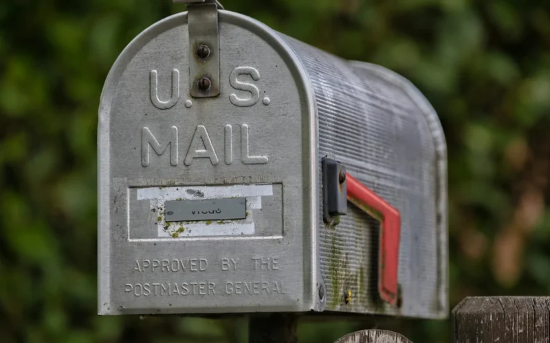 A weathered roadside mailbox with its red flag raised