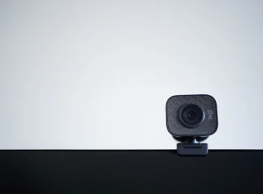 A webcam mounted on a desk monitor against a pale wall