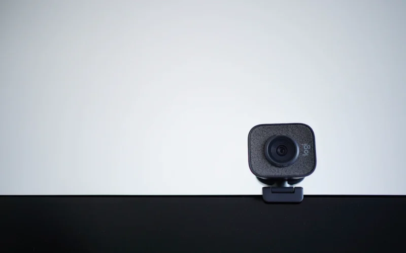 A webcam mounted on a desk monitor against a pale wall