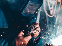 Welder in a protective mask working on metal as sparks fly