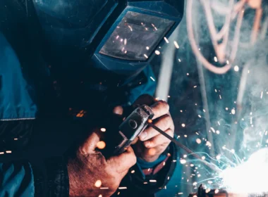 Welder in a protective mask working on metal as sparks fly