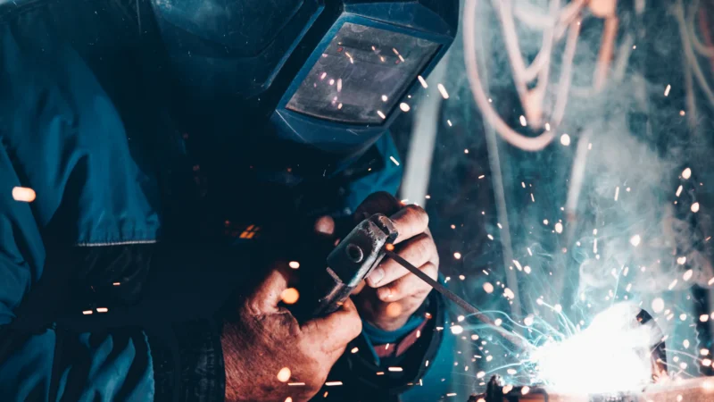 Welder in a protective mask working on metal as sparks fly