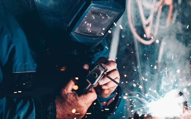 Welder in a protective mask working on metal as sparks fly