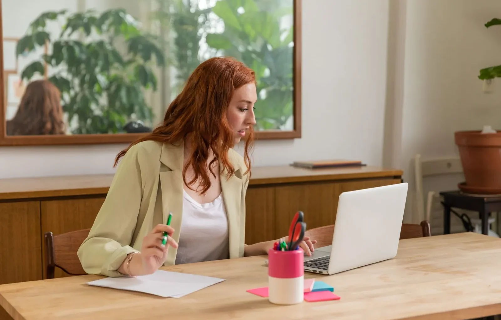 Woman working at a laptop with documents in a bright office, where Gemini in Chrome could read the open tab