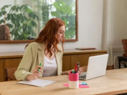 Woman working at a laptop with documents in a bright office, where Gemini in Chrome could read the open tab