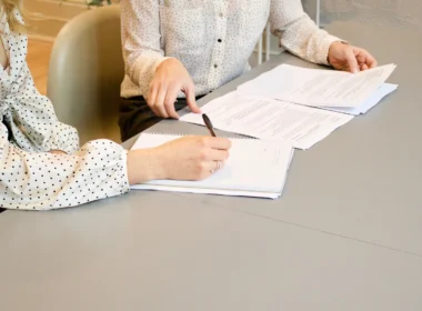 Woman signing a document beside another woman