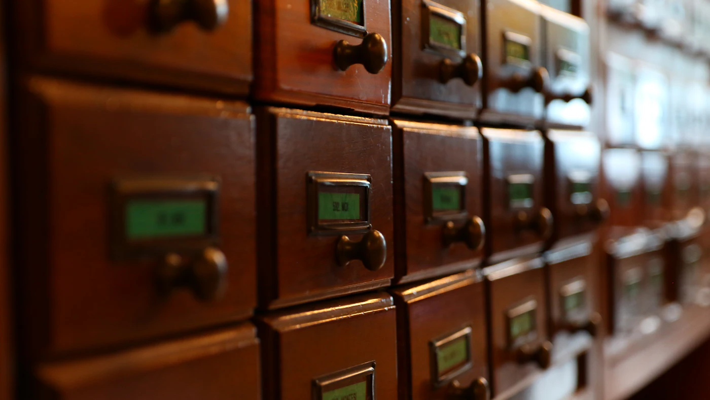 Rows of wooden card catalogue drawers, each with a small label holder