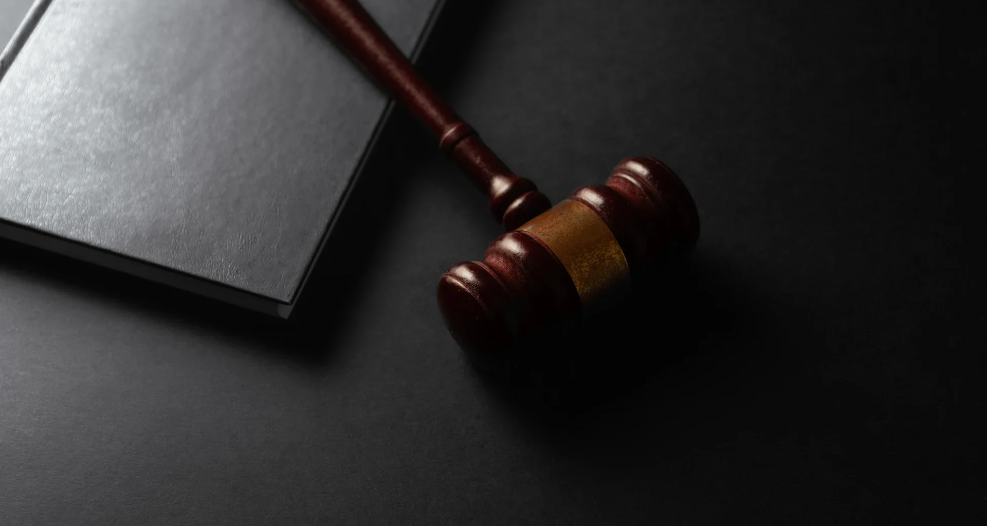 Wooden gavel resting on a dark surface next to book