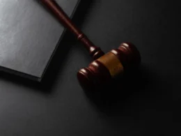 Wooden gavel resting on a dark surface next to book