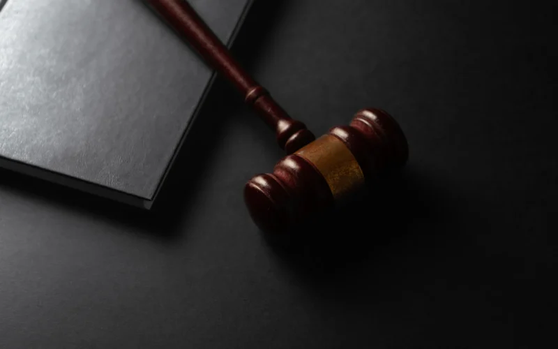 Wooden gavel resting on a dark surface next to book